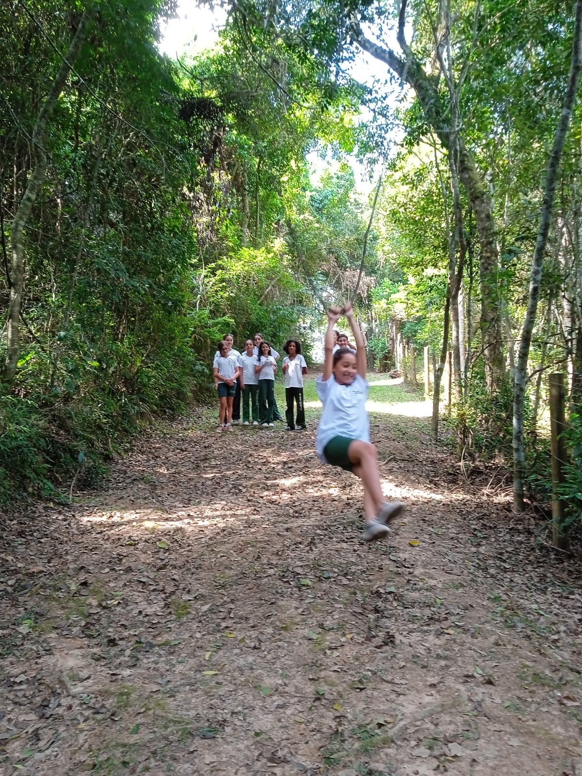 Aluna se divertindo em um balanço de corda durante trilha na mata do colégio