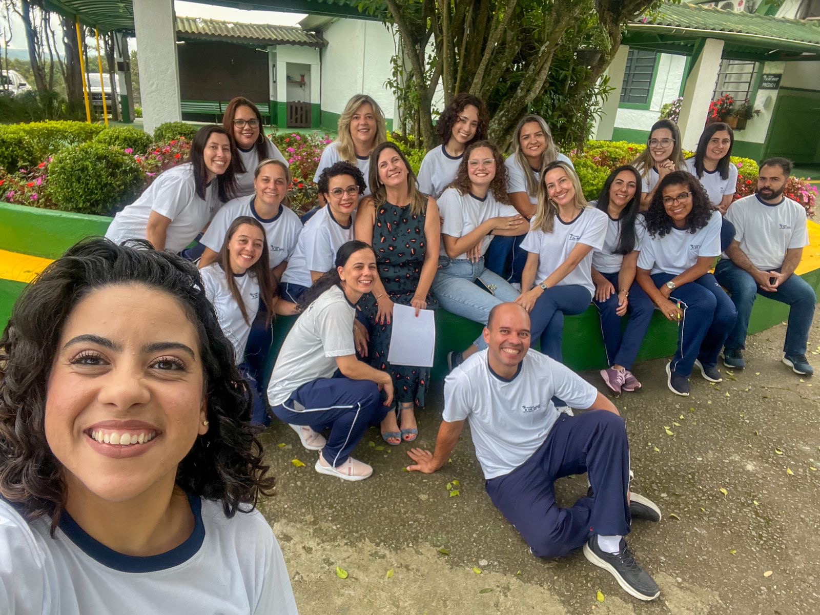 Equipe do Colégio 8 de Maio reunida e sorrindo em foto no jardim da escola